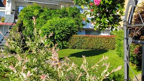 A residential building with a well-maintained garden, a hedge, and a staircase leading to an upper level.