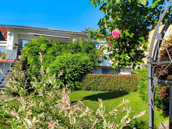 Un immeuble résidentiel doté d’un jardin bien entretenu, d’une haie et d’un escalier menant à un étage supérieur.