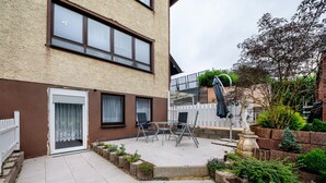 A courtyard with a patio table and chairs, a white picket fence, and a small garden area with plants. - "Pesch" Holiday Apartment with Shared Terrace (Nettersheim -Pesch)