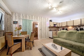 A living room with a dining table, chairs, a sofa, a kitchen area, and a bathroom visible through an open door. - Apartment "Pesch" with Shared Terrace & Wi-Fi (Nettersheim -Pesch)