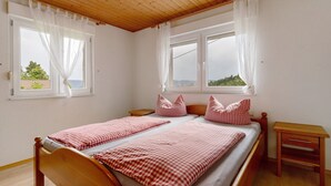 Un dormitorio con una cama de madera, dos mesitas de noche y una ventana con cortinas.