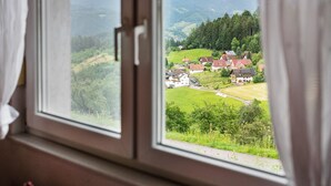 Una ventana con vistas a un paisaje rural, que incluye casas y vegetación.