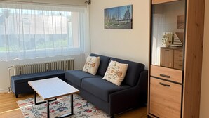 En moderne stue med en hjørnesofa, et træskab, et maleri og en radiator.