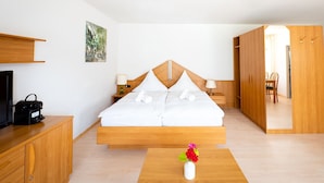 Een moderne hotelkamer met een houten bed, nachtkastjes, een televisie en een houten kledingkast.