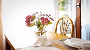 Een eettafel gedekt met borden, een kopje en een glazen schaal met bloemen.