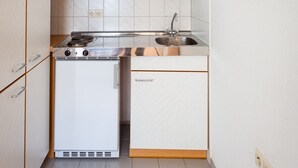 Een kleine keuken met witte kastjes, een fornuis en een spoelbak.