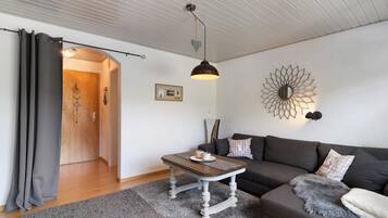 A living room with a sofa, a coffee table, a decorative wall piece, and a door leading to another room.