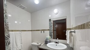 A modern bathroom with a toilet, sink, and shower area. - St. Lawrence Suites - Suite Three (Oistins)