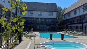 A swimming pool area with lounge chairs and a poolside deck. - 🦊Tiny, Mighty Studio in Canmore🦊  (Canmore)