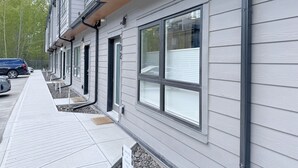 A modern building with large windows, a covered walkway, and a parked car. - 🦊Tiny, Mighty Studio in Canmore🦊  (Canmore)