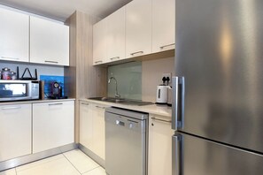 Una cucina moderna con elettrodomestici in acciaio inossidabile, tra cui una lavastoviglie e un frigorifero.