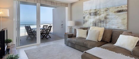 A living room with a sofa, a coffee table, a TV, and a painting.