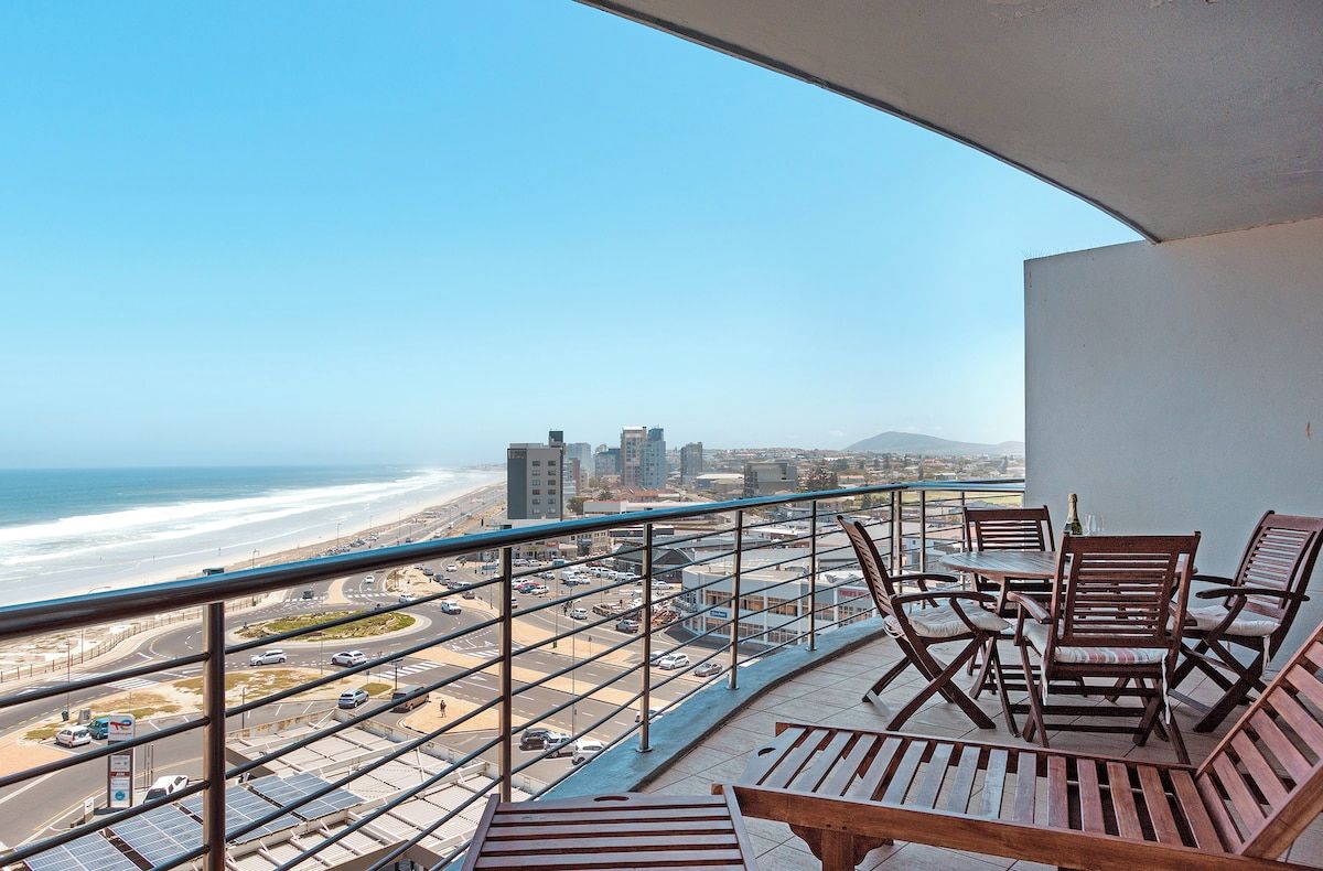 A balcony with a view of the beach and cityscape.
