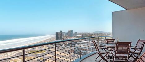 A balcony with a view of the beach and cityscape.