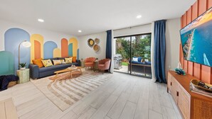 Una sala de estar moderna con un sofá, sillas, una mesa de centro y un televisor.