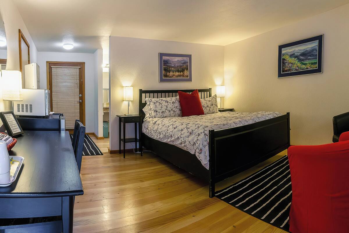 A hotel room with a bed, bedside tables, a desk, and a chair.
