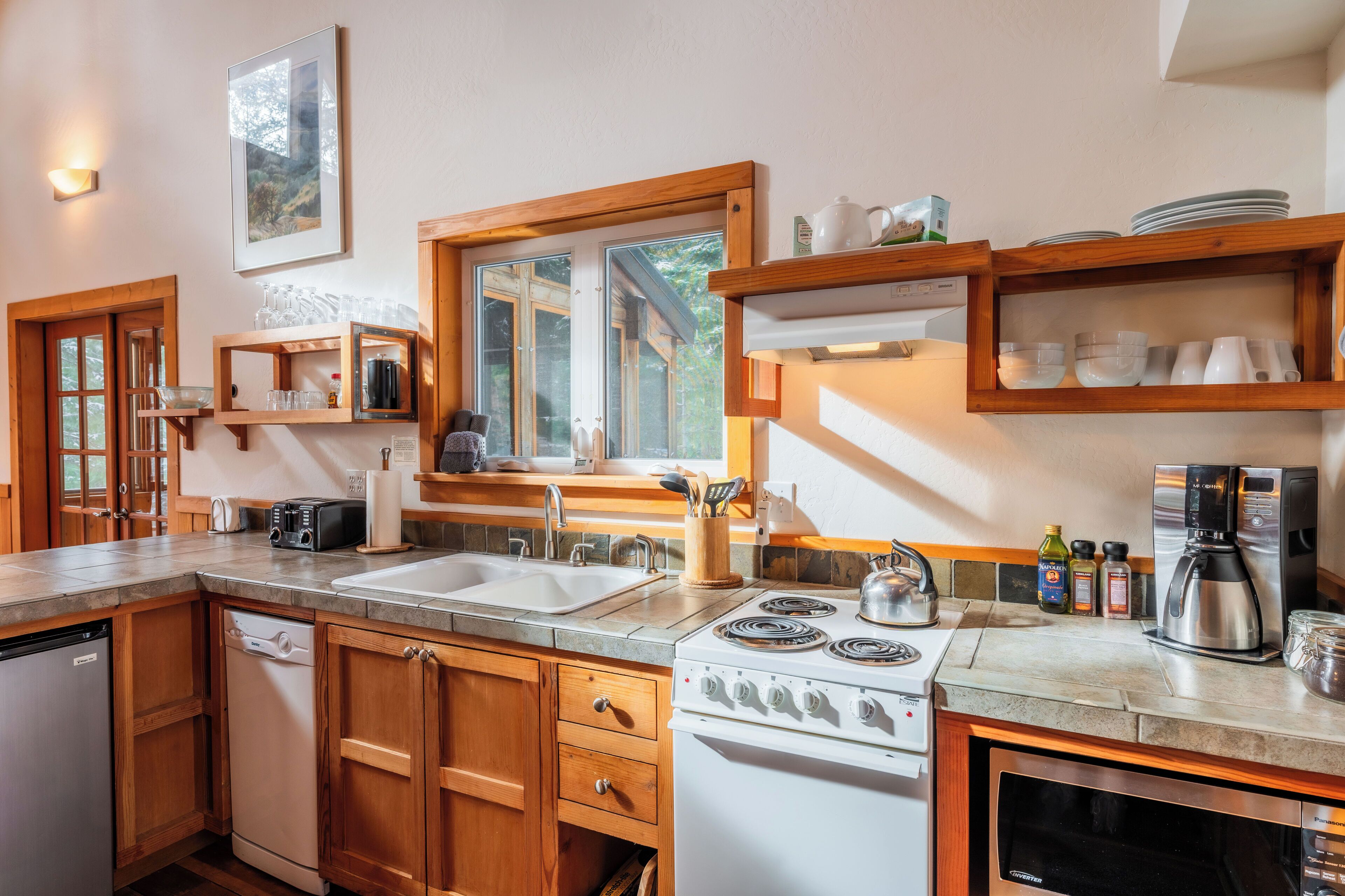 A kitchen with wooden cabinets, a double sink, a stove, and a coffee maker.