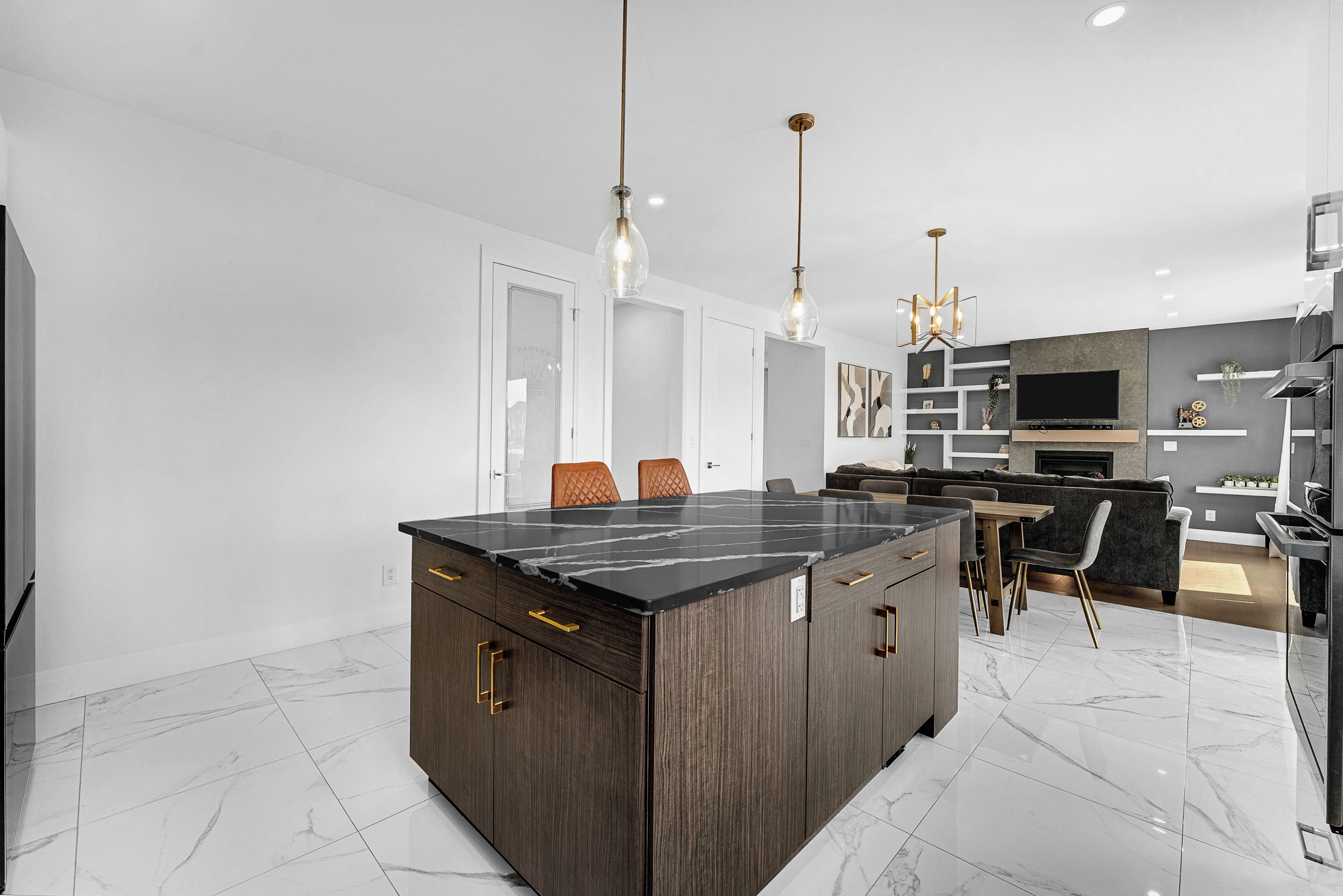 A modern kitchen with a central island, pendant lighting, and a dining area with a sofa and chairs.