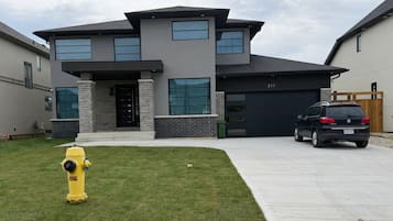 A modern two-story house with a garage, a driveway, and a yellow fire hydrant.