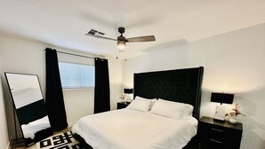 A bedroom with a large bed, a ceiling fan, a nightstand with a lamp, and a mirror. - StarryNight @ Museum Park -WORLD CUP- Walk to Museums, Hermann Park, Zoo, Dining (Houston)
