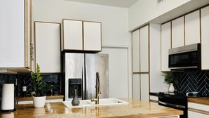 A modern kitchen with a central island, bar stools, a refrigerator, a microwave, and a sink. - StarryNight @ Museum Park -WORLD CUP- Walk to Museums, Hermann Park, Zoo, Dining (Houston)