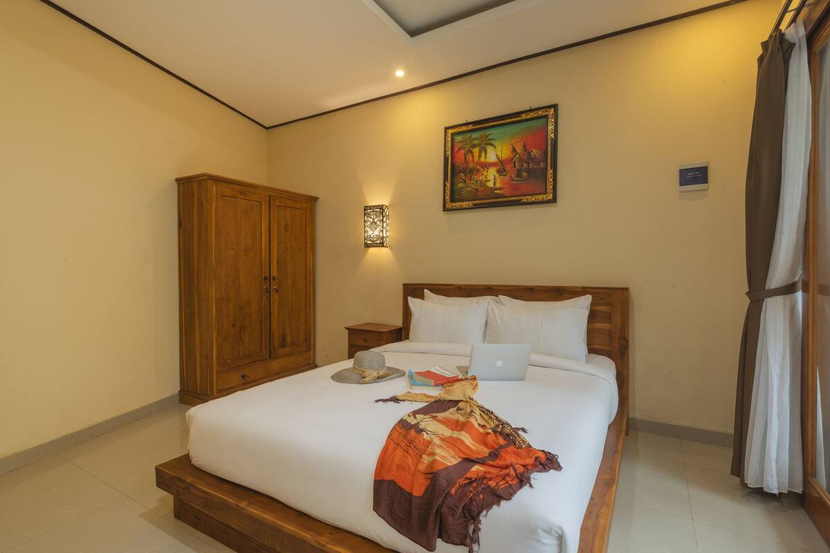 Un dormitorio con una cama grande, un armario de madera y un cuadro en la pared.