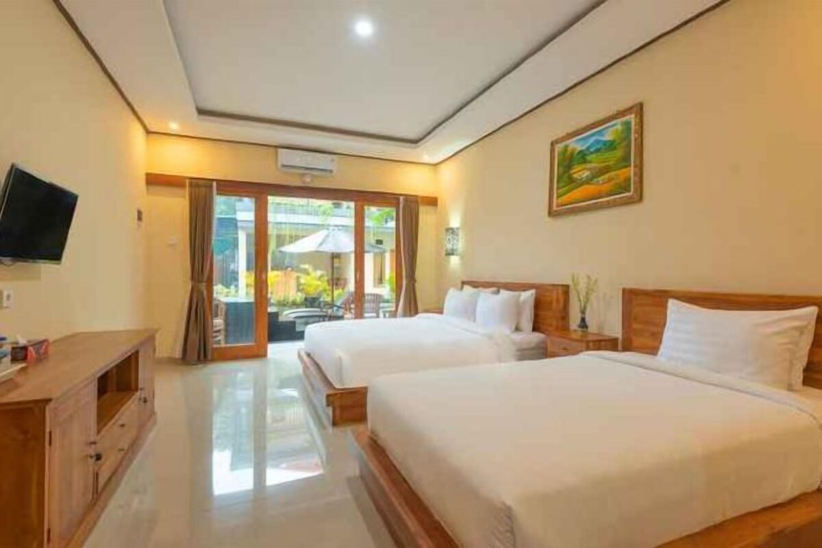 Habitación de hotel con dos camas, un televisor, un cuadro y vistas al exterior.