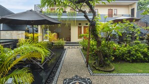 Ein Innenhof mit Wasserspiel, Kübelpflanzen und Sonnenschirmen.