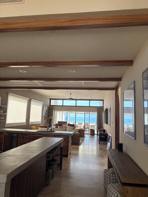 A spacious living area with a kitchen, dining area, and large windows offering a view of the ocean.