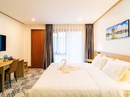 Una habitación de hotel con cama, escritorio, silla, televisión y un cuadro en la pared.