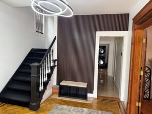 A staircase with black railings and white balusters, a bench, a wall with vertical slats, and a door leading to another room.