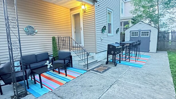 A covered patio with outdoor furniture, a grill, and a small shed. - Colonial Style Home 5 Br 2 bath n’ Parking! Close to restaurants n’ colleges! (Albany)