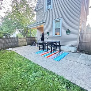 A house with a covered patio area featuring a table and chairs, a small garden, and a wooden fence. - Colonial Style Home 5 Br 2 bath n’ Parking! Close to restaurants n’ colleges! (Albany)