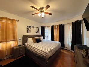 A bedroom with a bed, nightstands, a ceiling fan, and curtains. - Colonial Style Home 5 Br 2 bath n’ Parking! Close to restaurants n’ colleges! (Albany)