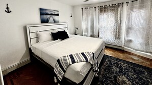 A neatly made bed with a striped blanket, a ceiling fan, and a painting above it. - Colonial Style Home 5 Br 2 bath n’ Parking! Close to restaurants n’ colleges! (Albany)