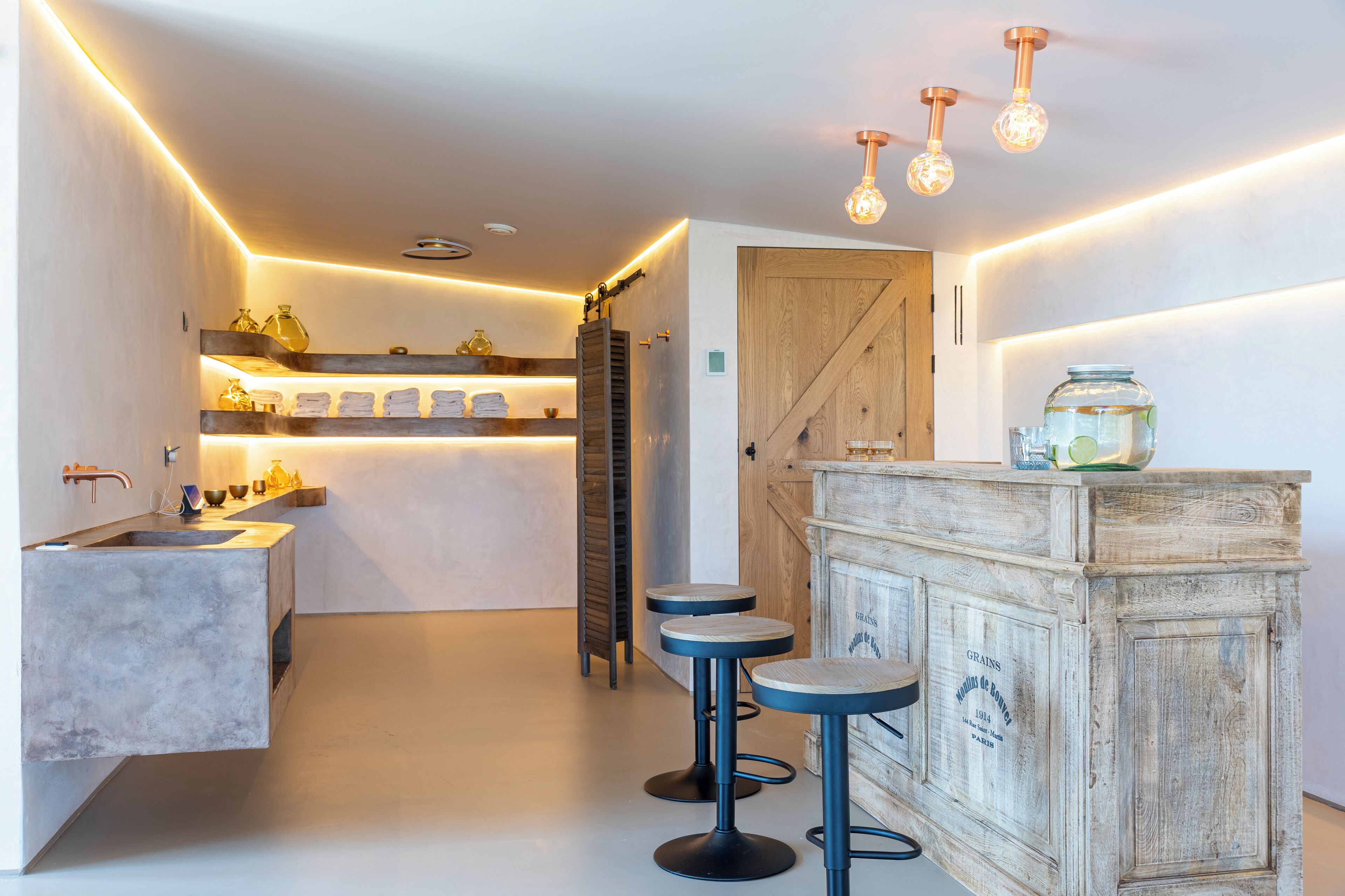 A modern kitchen with a central island, bar stools, and pendant lighting.