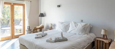 Une chambre d’hôtel avec un grand lit, une petite table avec une lampe, une chaise et une vue sur l’extérieur grâce à une porte coulissante.
