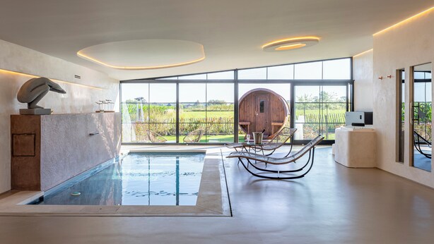 A modern indoor pool area with a view of a wooden barn and fields. - Burgemeestershof (Wetteren)