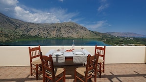 A dining table with chairs and a view of a lake and mountains. - Linda's Villa In Unrivalled position in Kournas - Amazing View! (Kavallos)