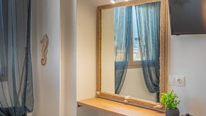 A bathroom with a wooden vanity, a mirror with a rope frame, and a small plant on the counter.