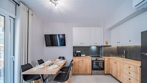 Eine moderne Küche mit Holzausstattung, einem Einbauofen und einem Essbereich mit Tisch für vier Personen.
