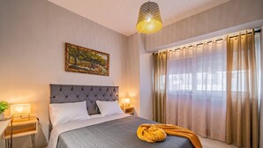 Ein ordentlich eingerichtetes Schlafzimmer mit einem Bett, Nachttischlampen, einem Gemälde und einem Fenster mit Vorhängen.