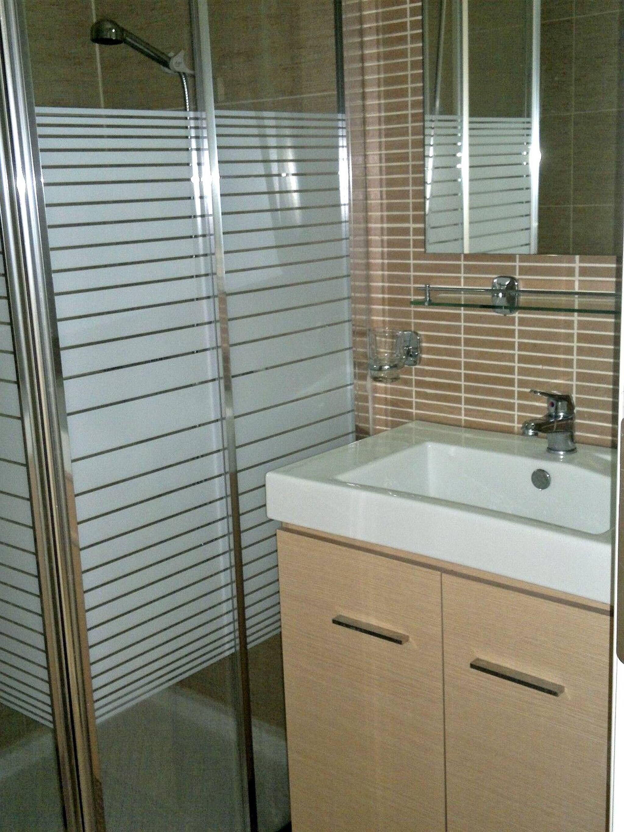 Une salle de bain avec une douche, un lavabo et un miroir.