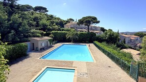 A rectangular swimming pool with a tiled deck, surrounded by greenery and residential buildings. - Apartment T2 - 3 people - Air conditioning - Pool and tennis residence - Unobstructed view -... (STE MAXIME)