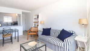 Un salon moderne avec un canapé à rayures, une table basse en verre et un coin repas avec des chaises.