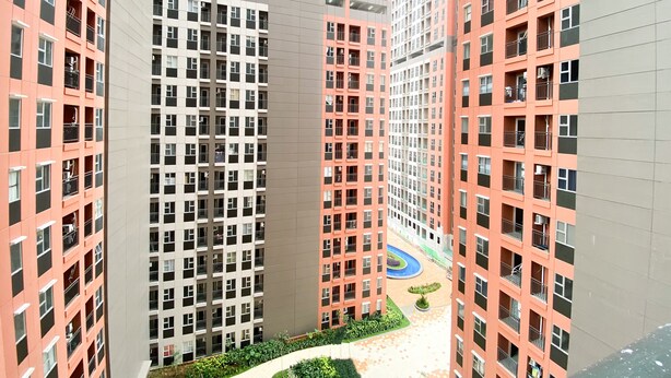 A high-rise residential building with multiple floors, balconies, and a central courtyard with a circular walkway. - Chic And Cozy Studio Apartment At Transpark Juanda Bekasi (Bekasi)