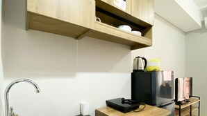 A modern kitchen with a stainless steel sink, wooden cabinets, and a black refrigerator. - Chic And Cozy Studio Apartment At Transpark Juanda Bekasi (Bekasi)
