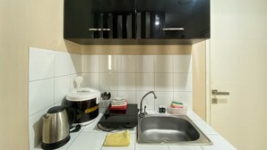A kitchen with a stainless steel sink, a kettle, a coffee maker, and a black cabinet above the counter. - Comfort And Elegant 4Br Combined At Springlake Summarecon Bekasi Apartment (Bekasi)