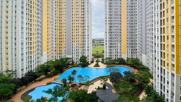 A high-rise residential building with a central swimming pool surrounded by greenery and pathways. - Comfort And Elegant 4Br Combined At Springlake Summarecon Bekasi Apartment (Bekasi)
