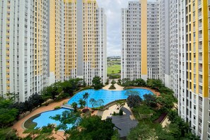 A high-rise residential building with a central swimming pool surrounded by greenery and pathways. - Comfort And Elegant 4Br Combined At Springlake Summarecon Bekasi Apartment (Bekasi)